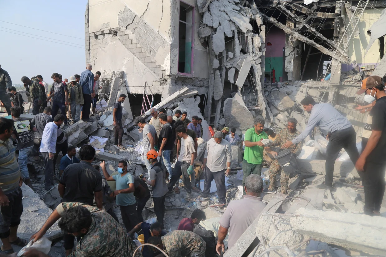 A crowd of Iranians by the rubble that used to be a girl's school.