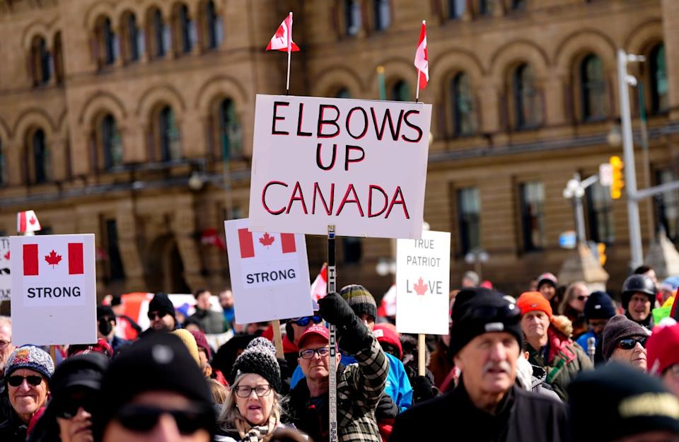 Canadian protesters marching and carrying 'Elbows Up' signs