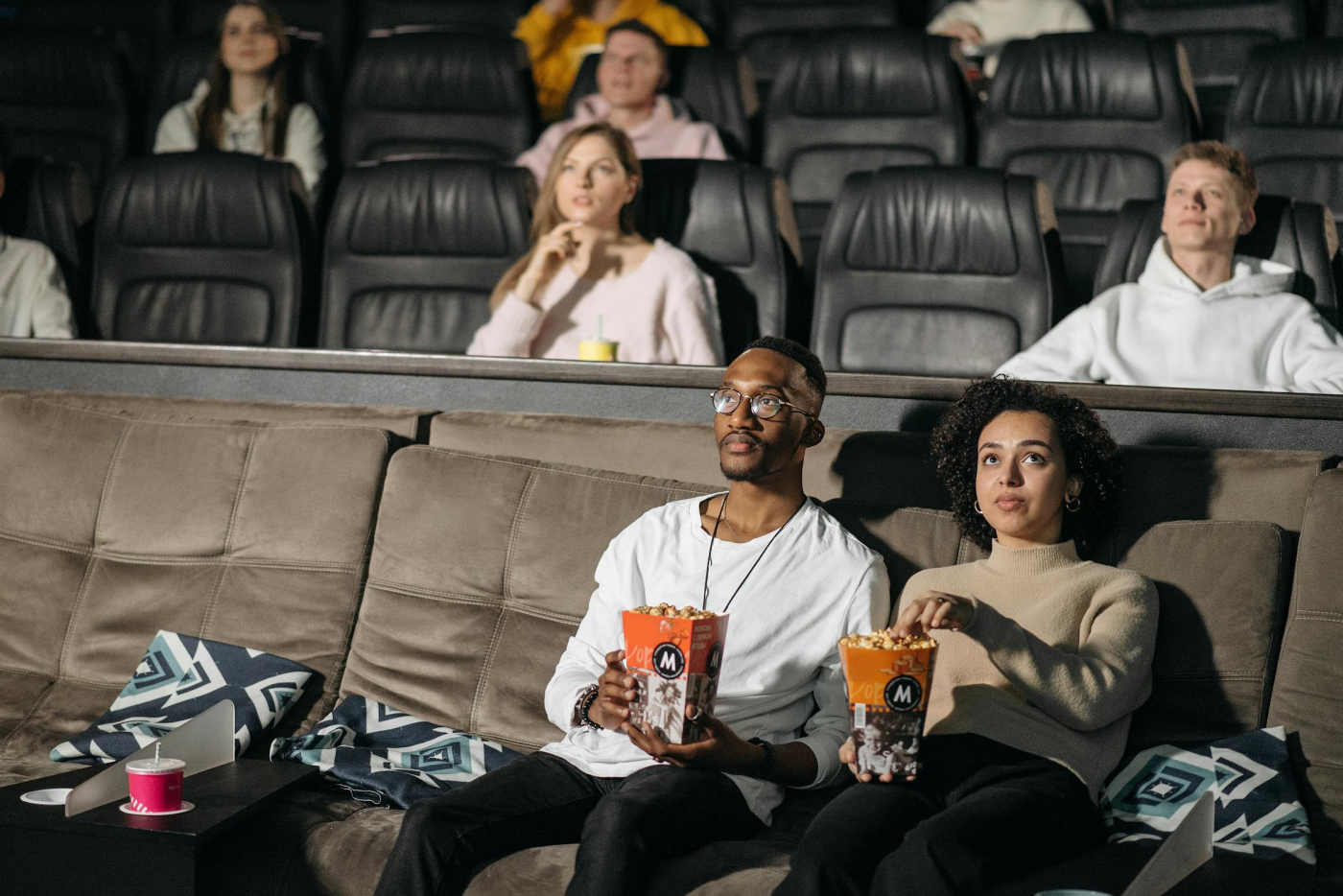 two people sitting in a movie theater eating popcorn